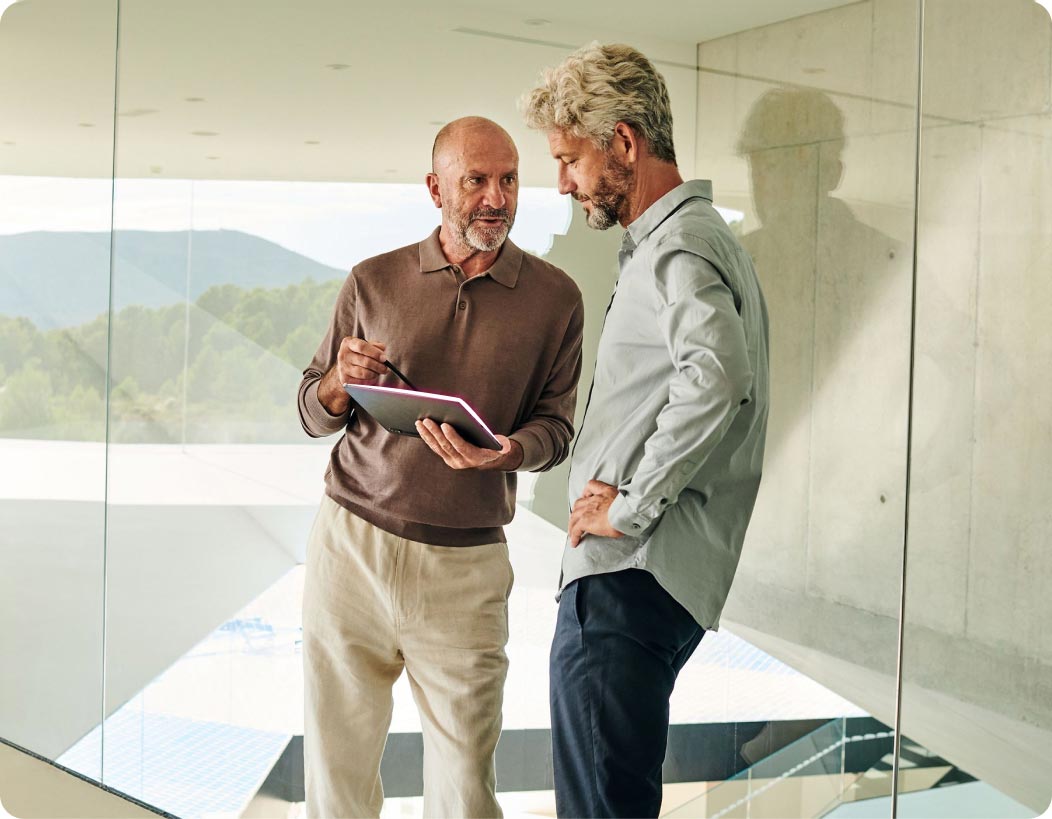 Zwei Männer schauen auf ein Tablet und besprechen den Glasfaseranschluss für gewerbliche Immobilien