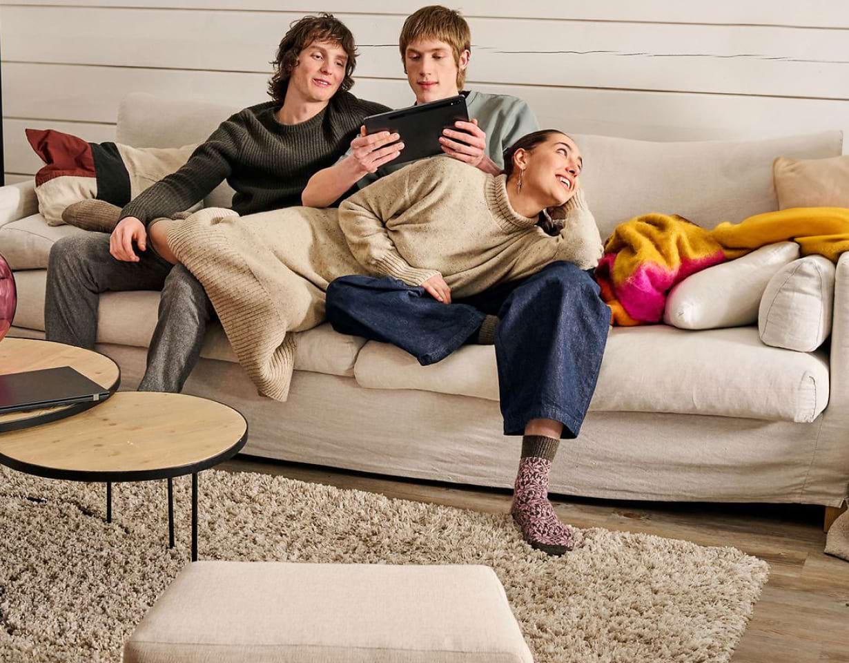 Drei junge Menschen sitzen mit einem Tablet auf der Couch