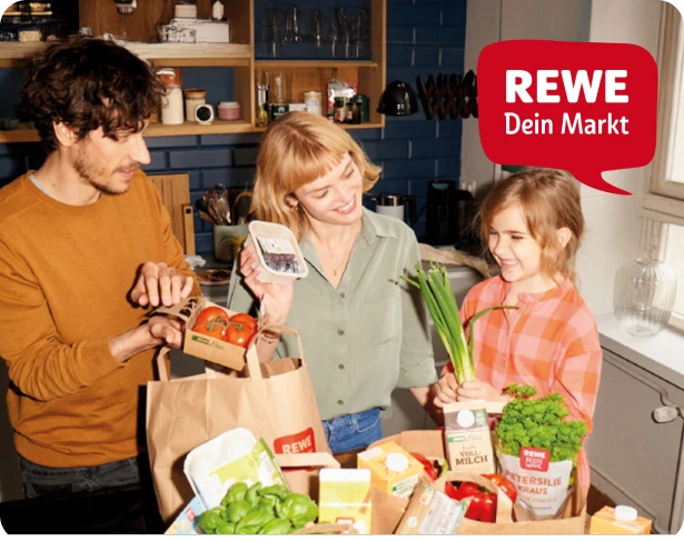 Einkaufsszene mit frischem Gemüse und REWE Tüten in der Küche.