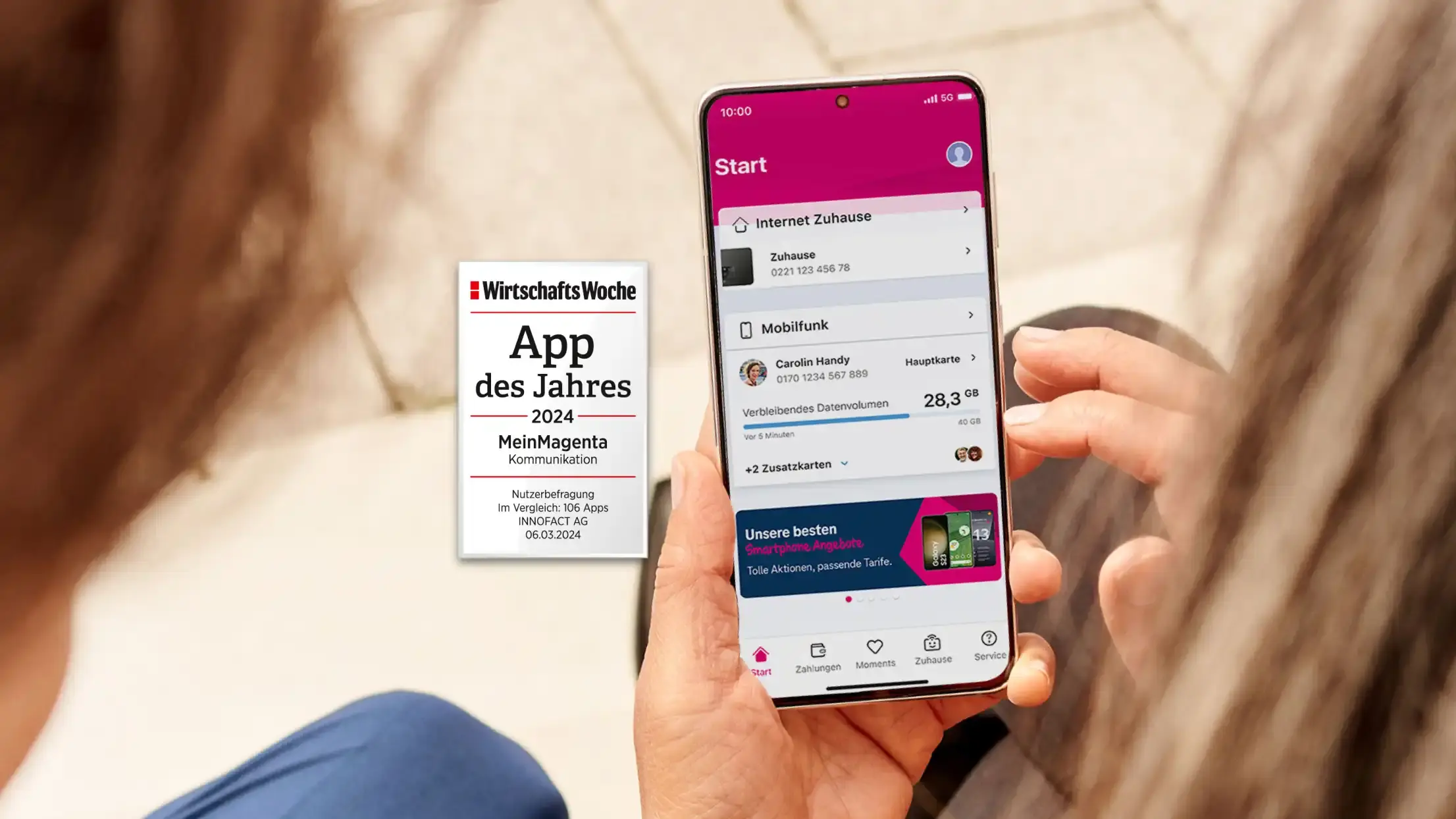 Eine Person hält ein Smartphone in der Hand und nutzt die „MeinMagenta“-App der Telekom. Auf dem Bildschirm sind Informationen zu Internet und Mobilfunk, einschließlich verbleibendem Datenvolumen, sichtbar. Links neben dem Handy ist ein Award von WirtschaftsWoche eingeblendet: „App des Jahres 2024 – MeinMagenta – Kommunikation“, basierend auf einer Nutzerbefragung unter 106 Apps von INNOFACT AG, datiert auf den 06.03.2024.