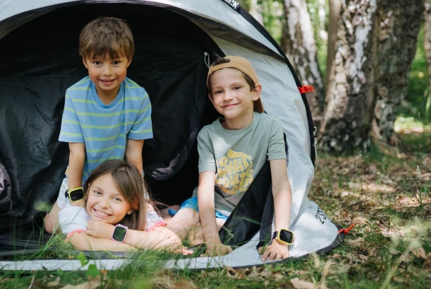 Zwei Kinder sind in der Natur. Eines der Kinder trägt die Kids Watch XPLORA X6 am Handgelenk. Beide Kinder schauen sich die Uhr an.