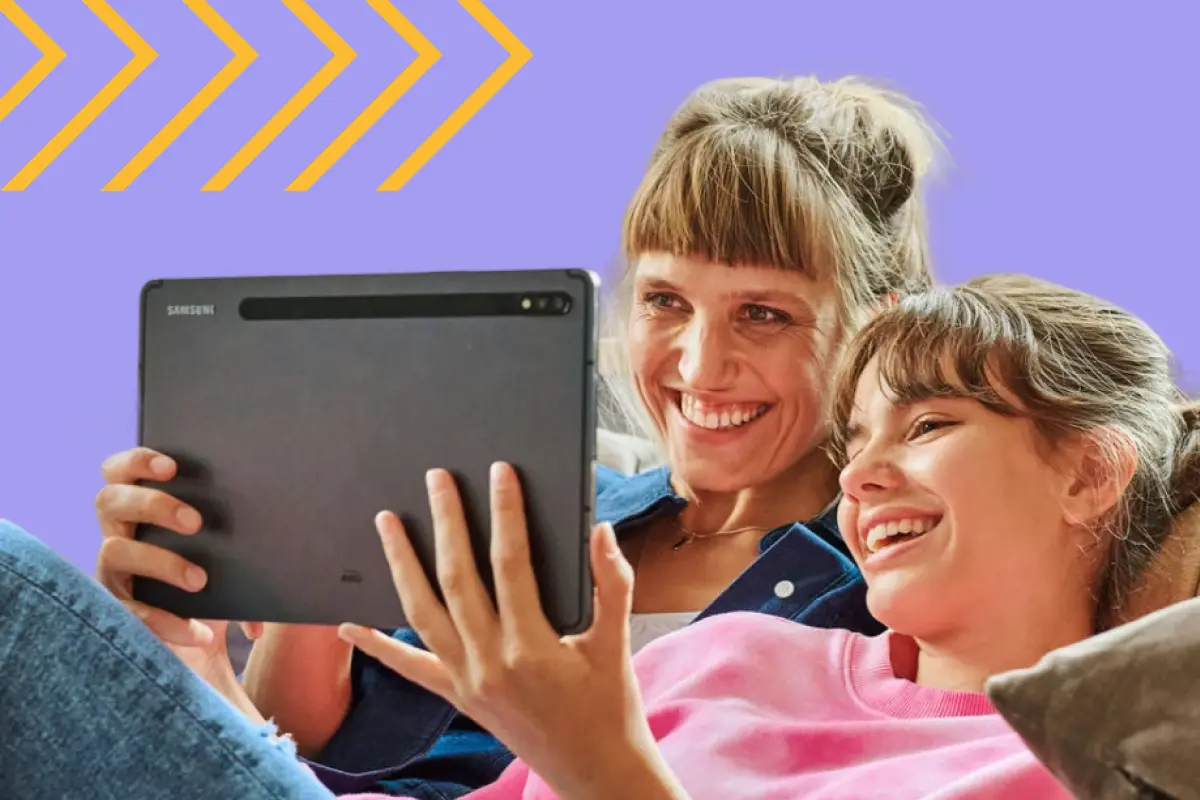 Zwei lachende Personen schauen gemeinsam auf ein Tablet.
