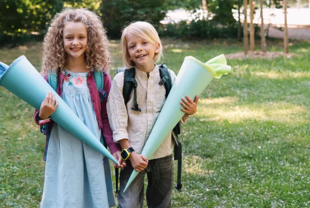 Zwei Kinder sind in der Natur. Eines der Kinder trägt die Kids Watch XPLORA X6 am Handgelenk. Beide Kinder schauen sich die Uhr an.