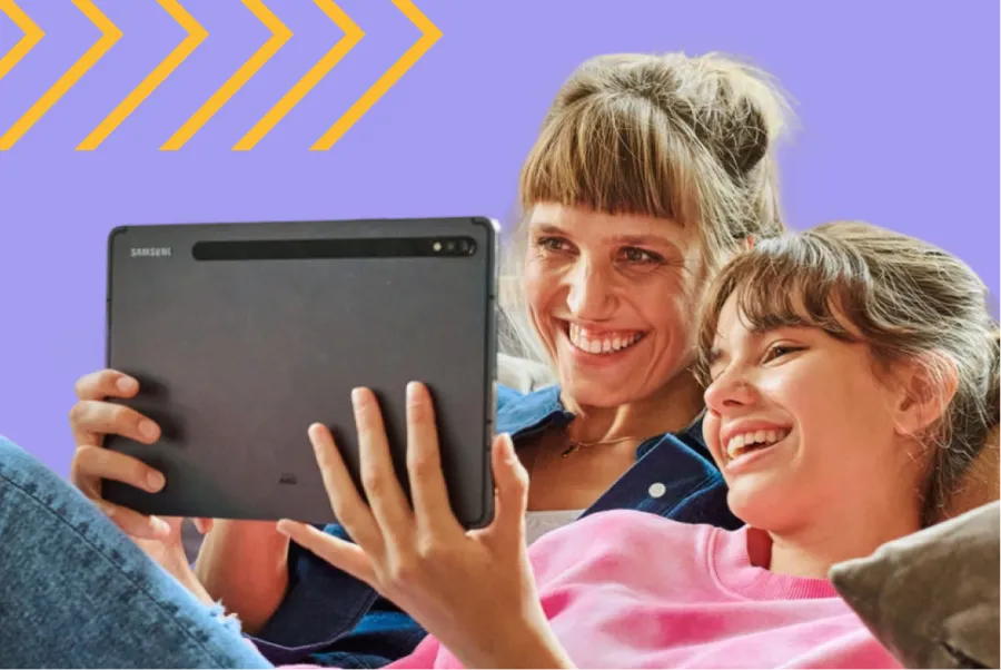 Zwei lachende Personen schauen gemeinsam auf ein Tablet.