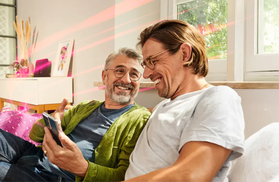 Zwei lachende Personen schauen gemeinsam auf ein Tablet.