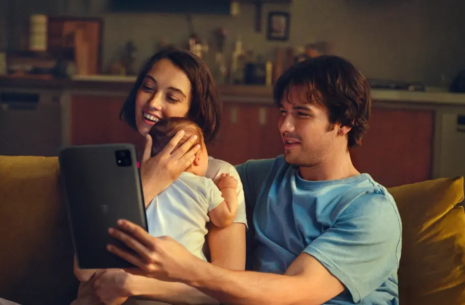 Zwei lachende Personen schauen gemeinsam auf ein Tablet.