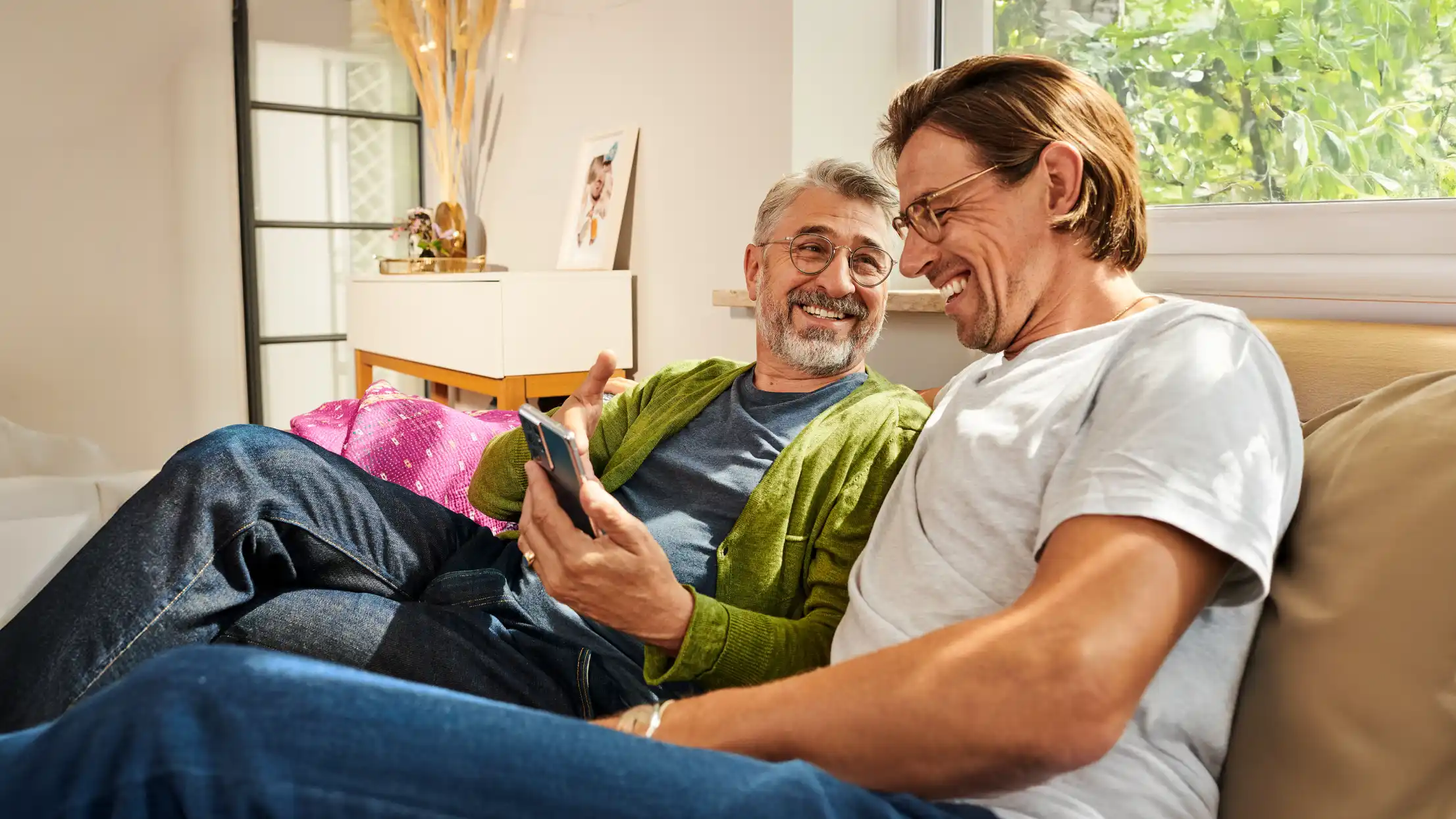 Zwei Männer schauen fröhlich auf ein Smartphone