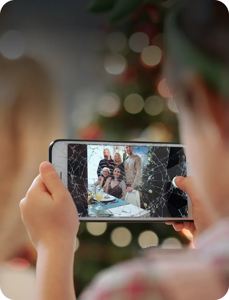 Eine Person macht mit einem Handy ein Foto zu Weihnachten, das Display ist kaputt