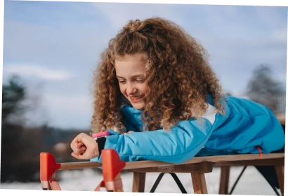 Kleiner Junge und kleines Mädchen, die auf einer Bank sitzen und sich gemeinsam die XPLORA X6 Play am Handgelenk des Jungen anschauen.
