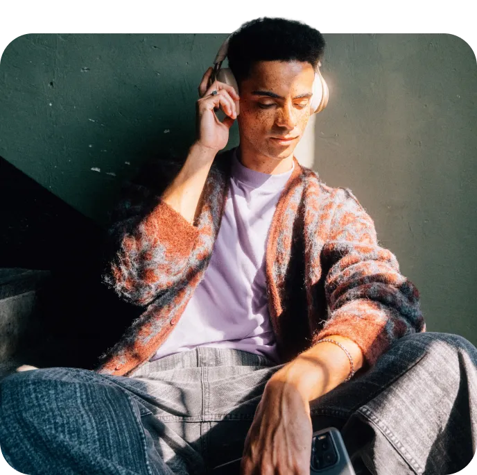 Junger Mann mit Kopfhörern sitzt auf einer Treppe.