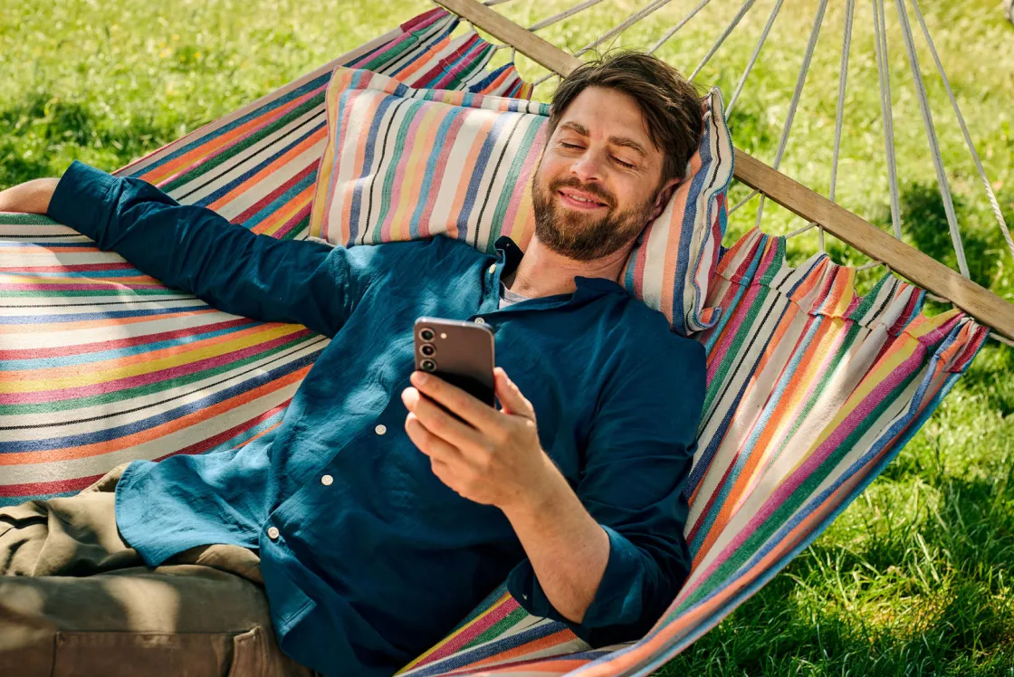 Mann am Meer, der ein Smartphone mit Dual-SIM in der Hand hält.