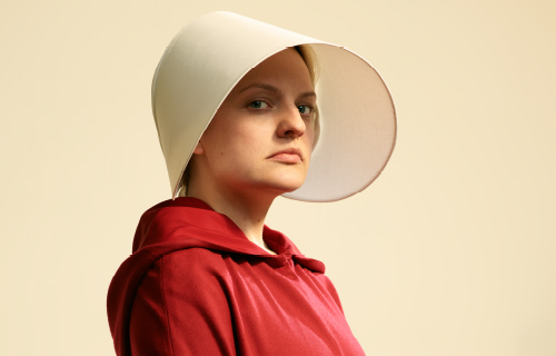 Elisabeth Moss als Desfred im roten Kleid der Mägde und weißer Kappe Elisabeth Moss als Desfred im roten Kleid der Mägde und weißer Kappe