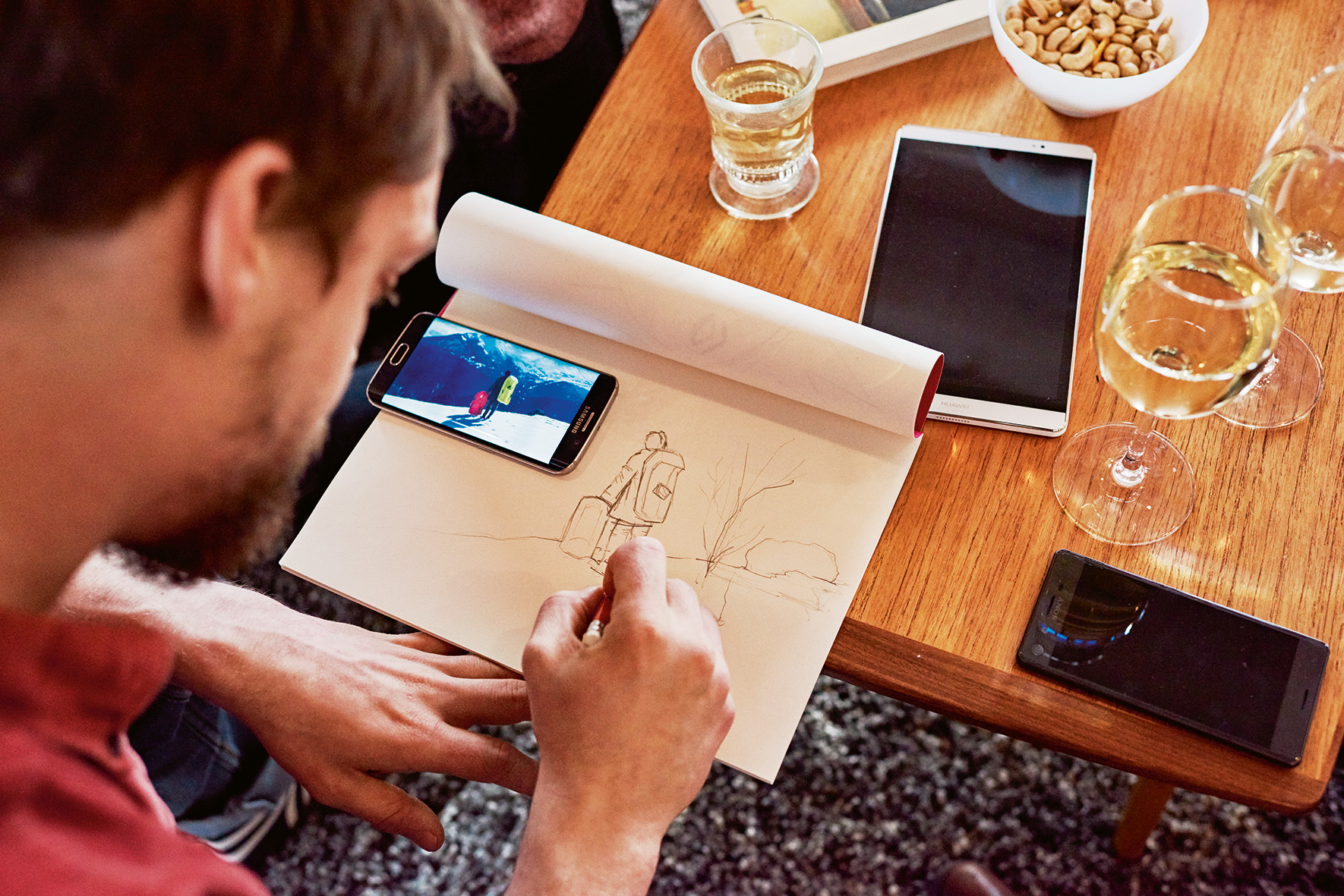 Mann arbeitet mit Smartphone an einer Zeichnung
