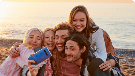 Junge Menschen machen ein Gruppenselfie am Strand