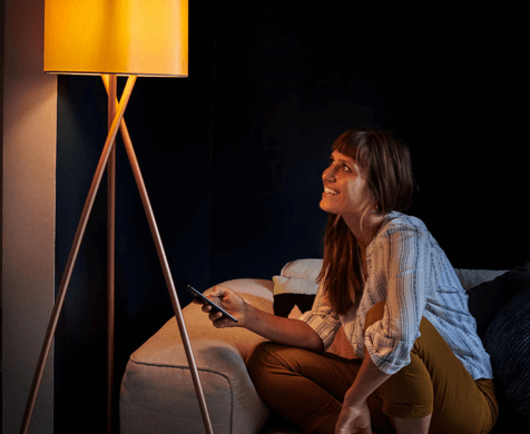 Eine Frau steuert eine Lampe im Smart Home dank Lichtsteuerung im Mesh-Netzwerk