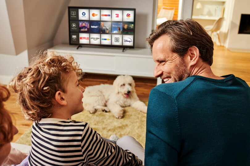 Eine Familie sitzt auf der Couch und schaut MagentaTV