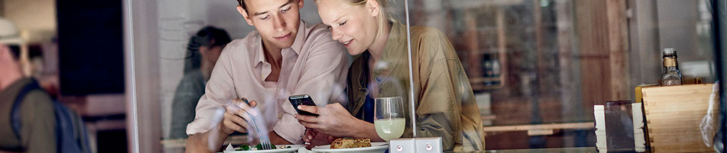 junges-paar-nutzt-smartphone-im-restaurant