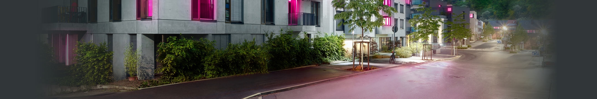 In magenta beleuchtete Wohnstraße - Text 'Hier ist MagentaZuhause', Thema Breitbandausbau